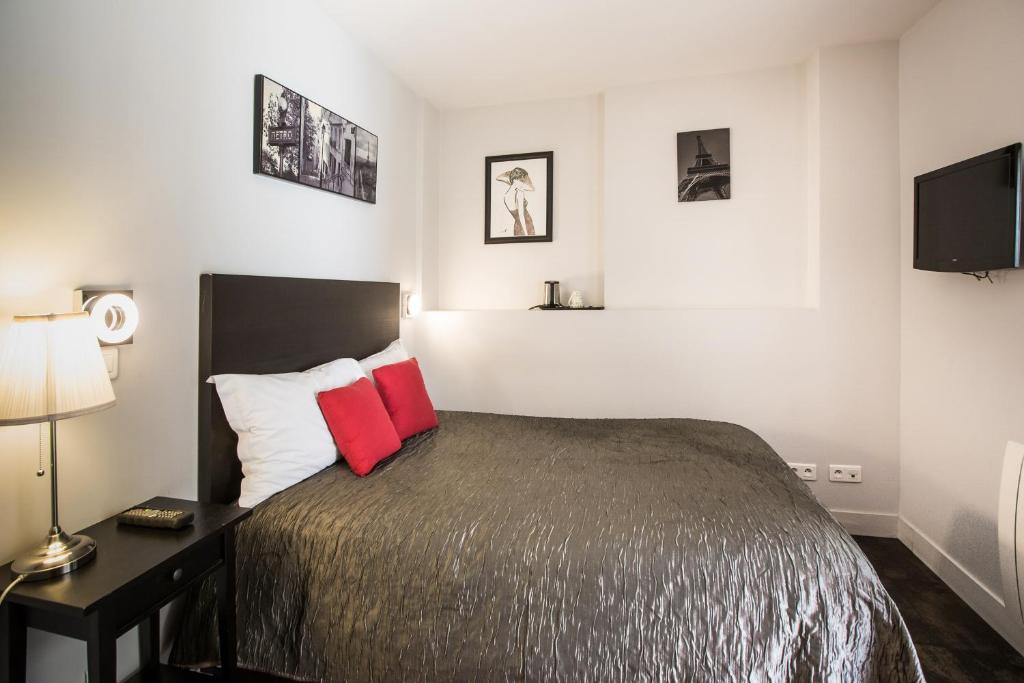 a bedroom with a bed with two red pillows at Le Figuier in Ivry-sur-Seine