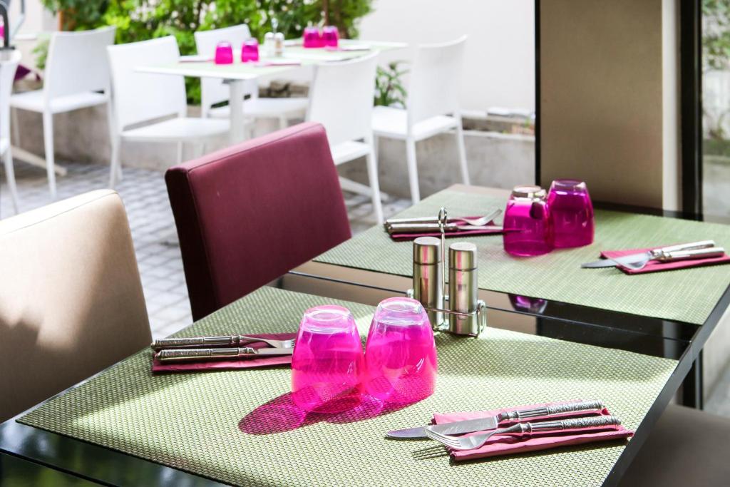 two tables in a restaurant with pink glasses and napkins at Le Figuier in Ivry-sur-Seine