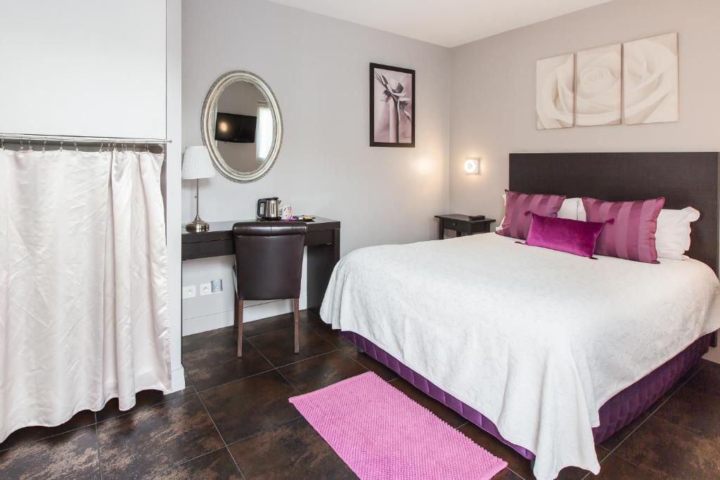 - une chambre avec un grand lit, des oreillers roses et un miroir dans l'établissement Le Figuier, à Ivry-sur-Seine