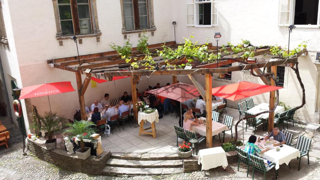 グラーツにあるMinihotel Grazのテーブルとパラソルに座る人々が座る屋外レストランを提供しています。