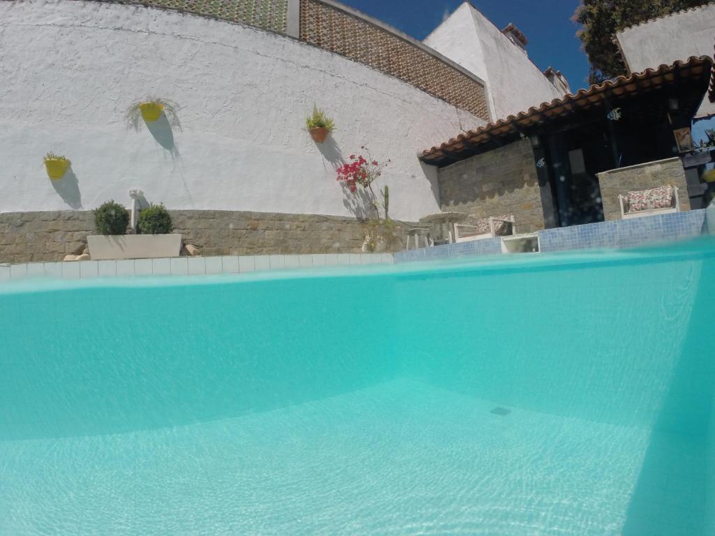 a blue swimming pool in front of a white wall at Rock n Hostel in Cabo Frio