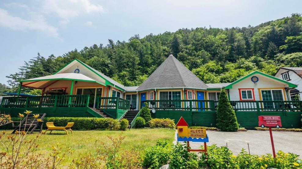 a large green house with a porch and a house at Charm Pension in Gapyeong
