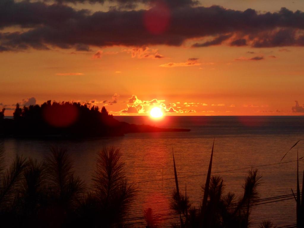 una puesta de sol sobre un cuerpo de agua con la puesta de sol en Minami Onna Tropical en Onna