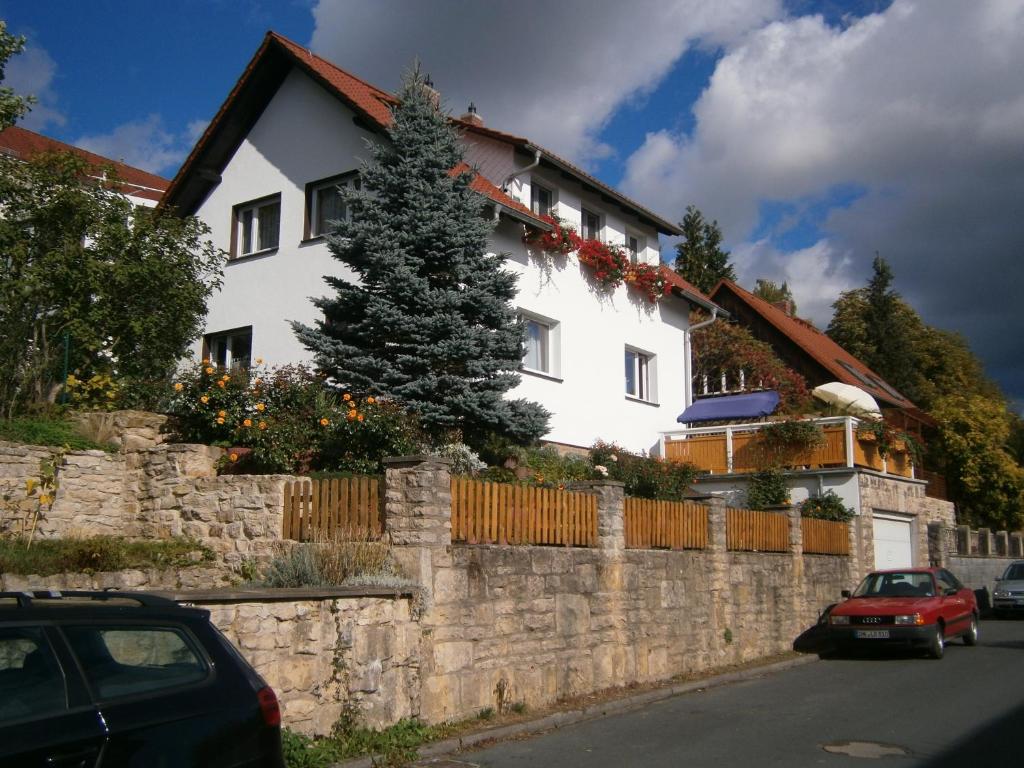 a white house with a fence and a tree at Ferienwohnung Fischer in Jena