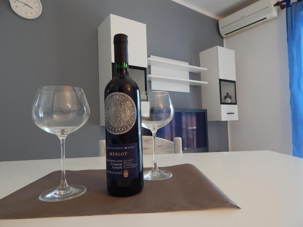uma garrafa de vinho sentada numa mesa com dois copos em Apartment Martina em Rab