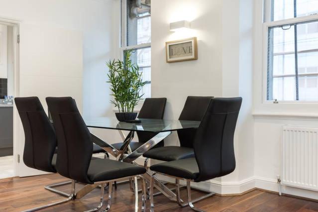 a dining room table with black chairs and a plant at Fleet Street Apartment 2 in London