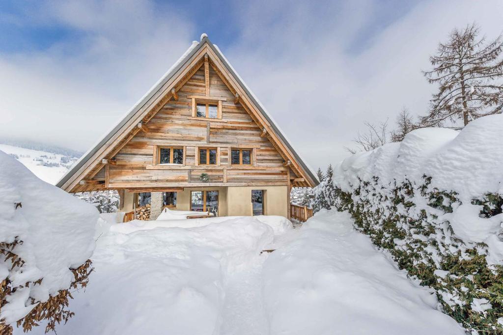 ムジェーヴにあるChalet Hermineの雪に覆われた茂みのあるログキャビン