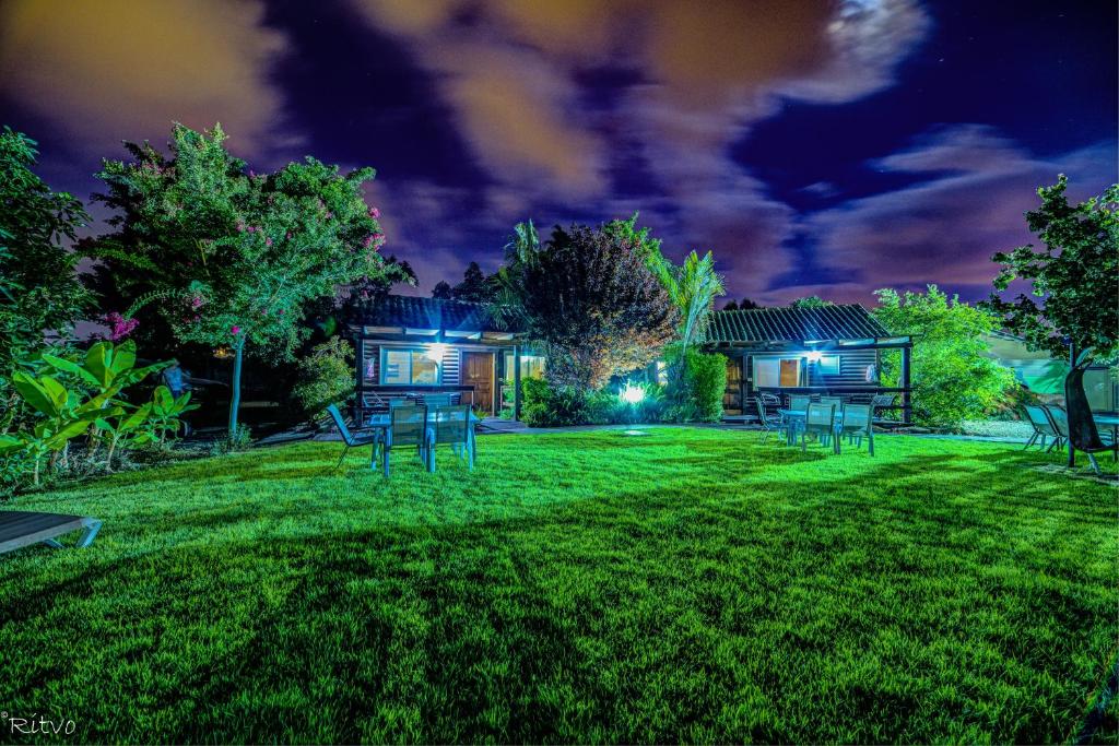 a yard with chairs in front of a house at night at Chalet The Mountain To The Sea in Beẕet