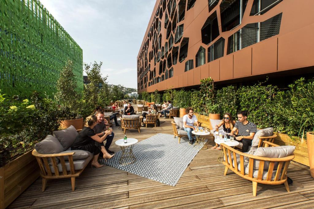 un grupo de personas sentadas en un patio fuera de un edificio en MOB HOTEL Lyon Confluence, en Lyon