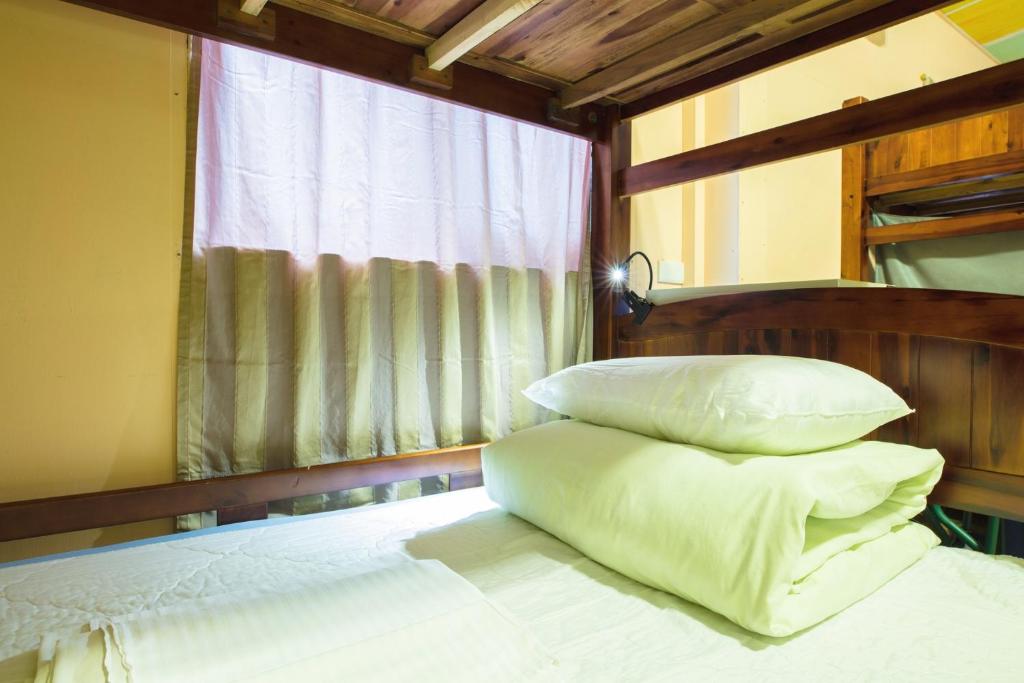 a bedroom with a bed with pillows and a window at On My Way Jiufen Youth Hostel in Jiufen