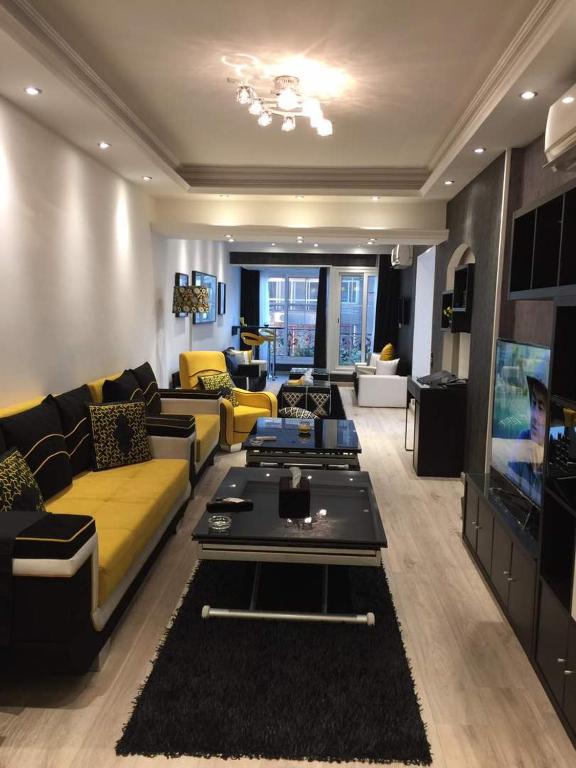 a living room with yellow couches and a tv at Luxury Mohandeseen Apartment in Cairo