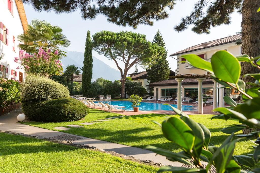 een tuin met een zwembad en een huis bij Romantik Hotel Oberwirt in Marlengo