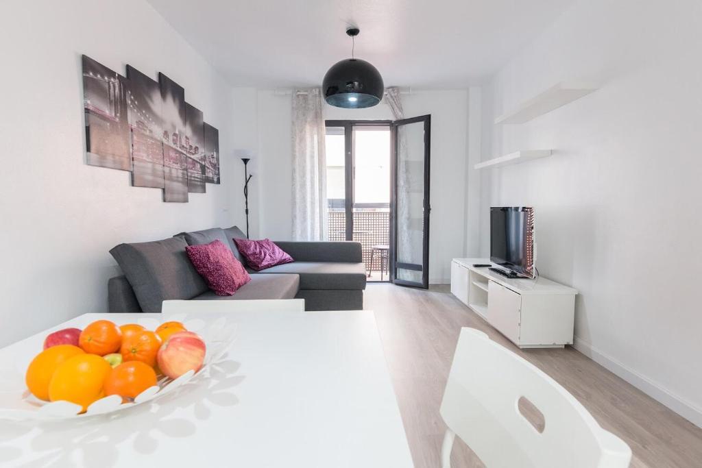 a white living room with a bowl of fruit on a table at Apartamento Galicia in Murcia