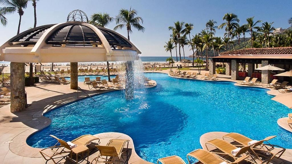 a swimming pool with a pool table and chairs at Pierre Mundo Imperial Riviera Diamante Acapulco in Acapulco