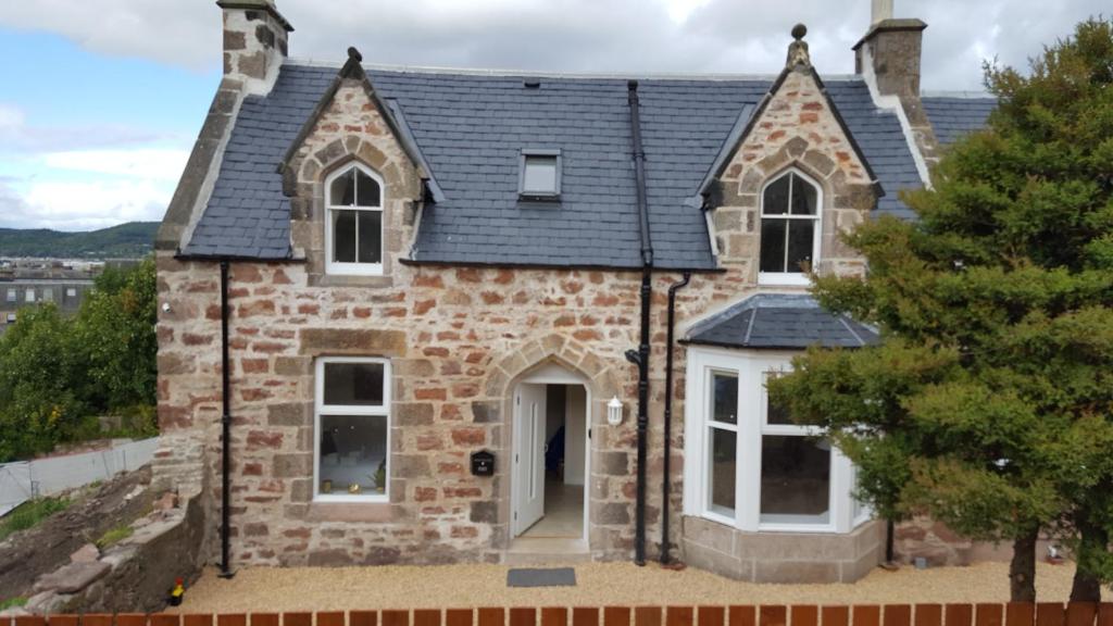 Casa de ladrillo con ventanas blancas y techo en View Cottage en Inverness