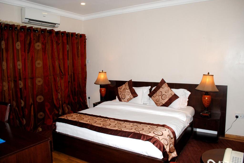 a bedroom with a large bed with a red curtain at Grand Inn & Suites in Ijebu Ode