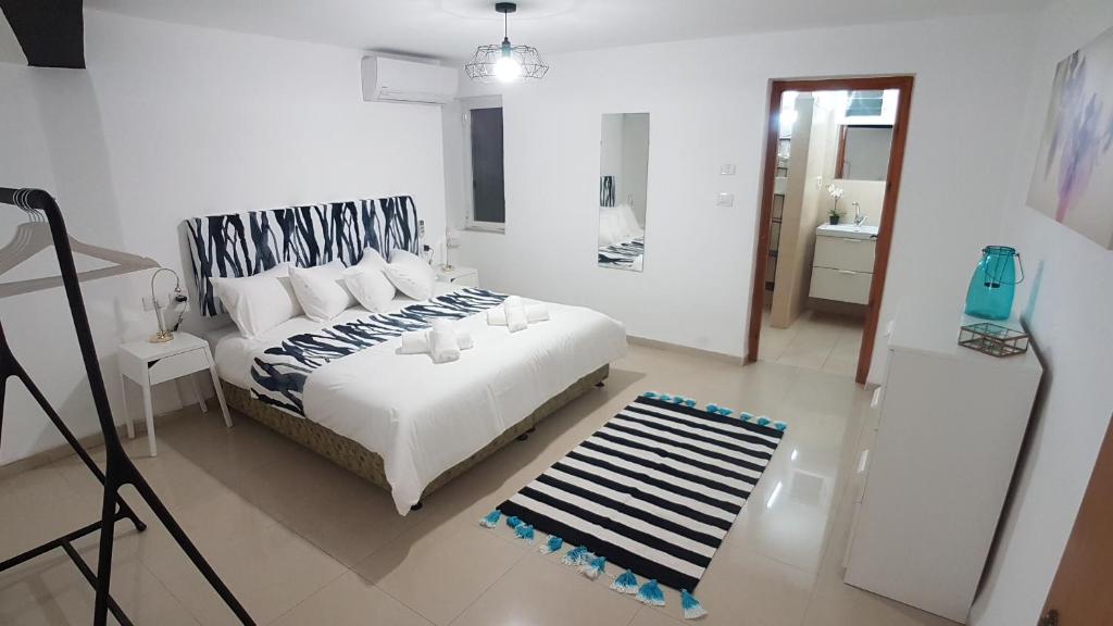 een slaapkamer met een wit bed en een zwart-wit tapijt bij Hili Apartments in Tiberias