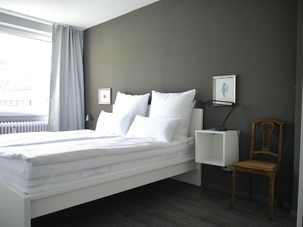 a bedroom with a white bed with a chair and a window at Lebendiges Linden in Hannover