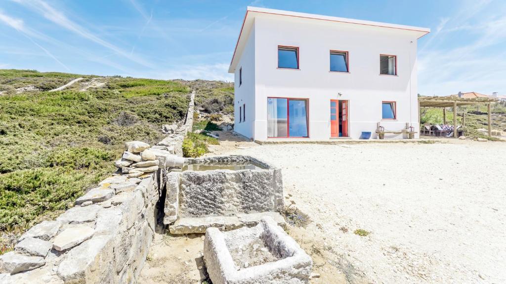 una casa bianca sulla spiaggia con una parete di roccia di Magoito1 a Sintra