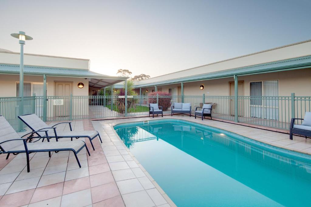 a swimming pool with lounge chairs and chairs next to a building at Best Western Crystal Inn in Bendigo