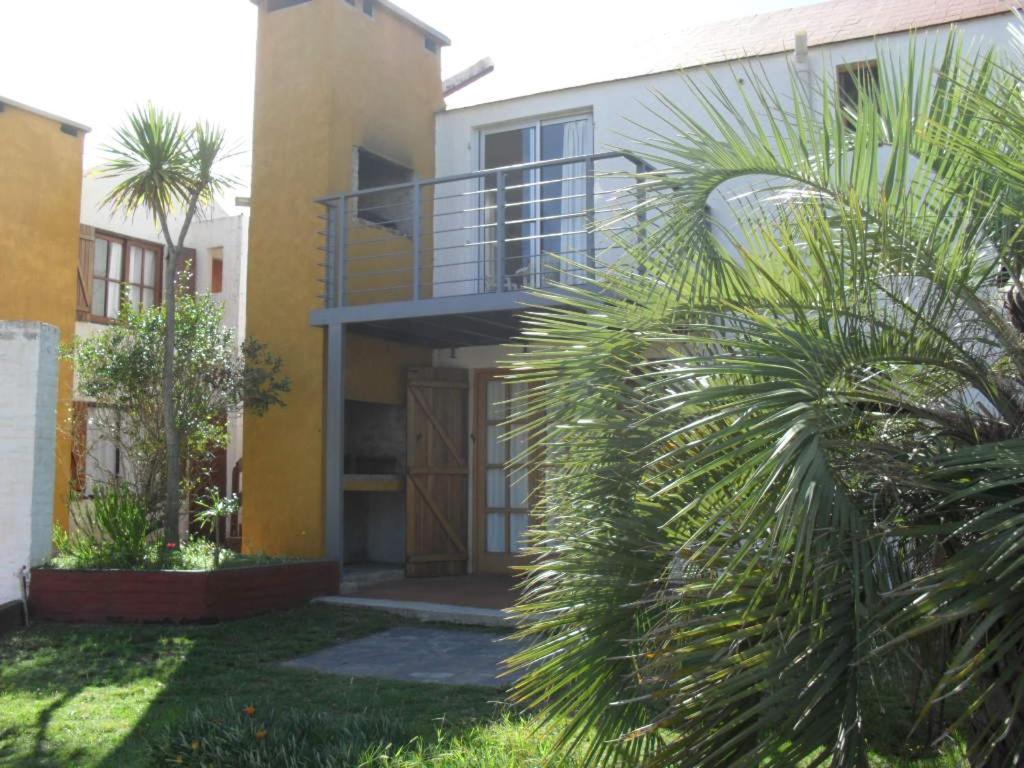 a house with a balcony and a palm tree at Alquileres Piriapolis in Piriápolis