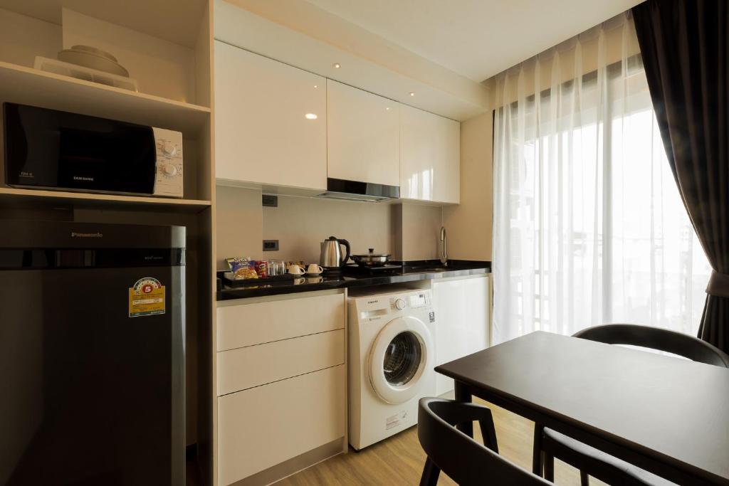 A compact apartment kitchen with a washing machine, appliances, and a small dining table.