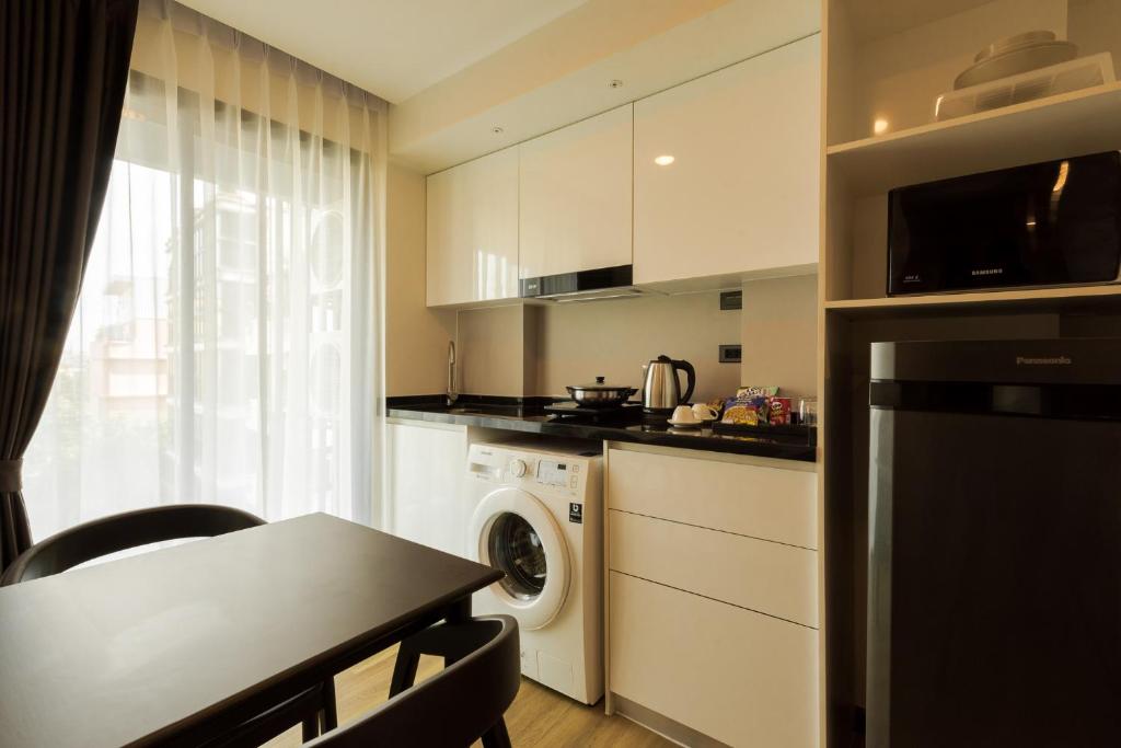 A compact kitchen-dining area with a washer, microwave, refrigerator and small table.