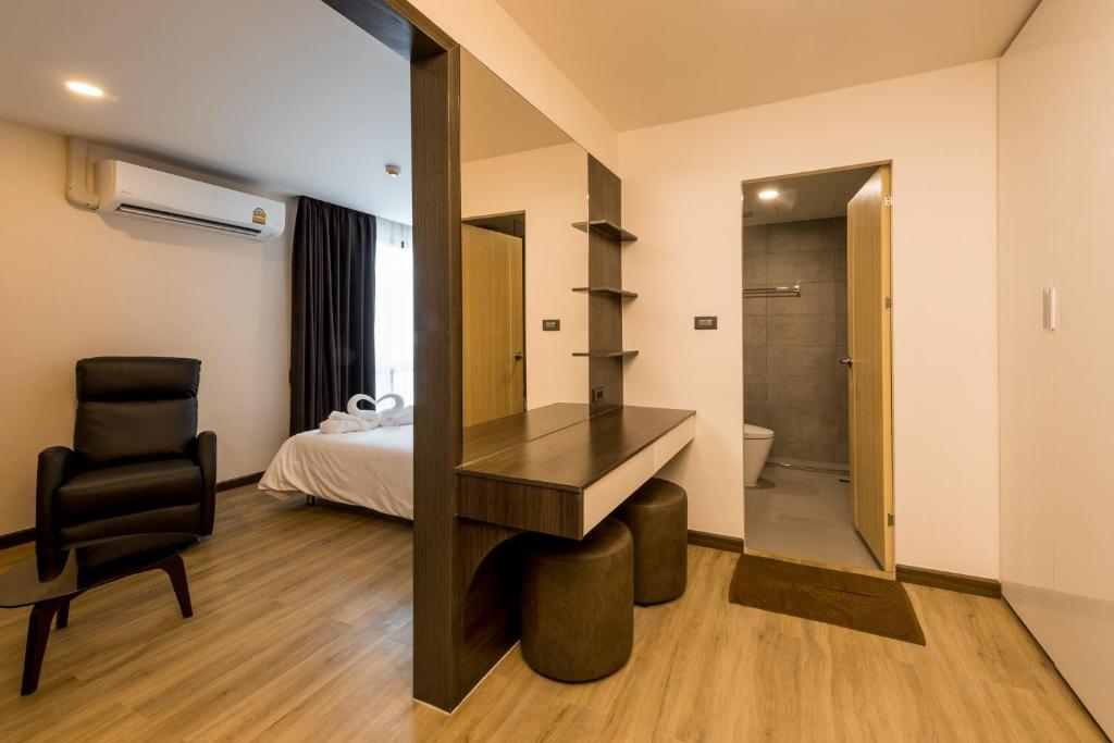 A bedroom entrance view showing a built-in desk, stool, armchair and ensuite doorway.
