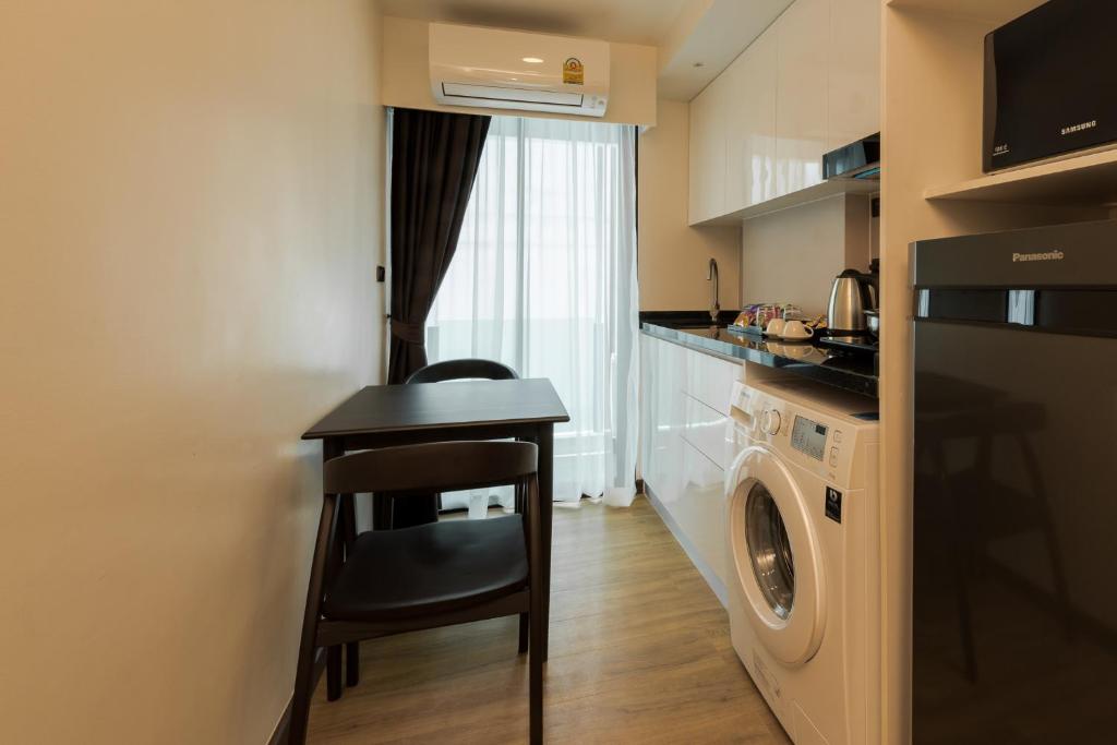 A narrow kitchenette with a two-seat table, washing machine and full-size refrigerator.