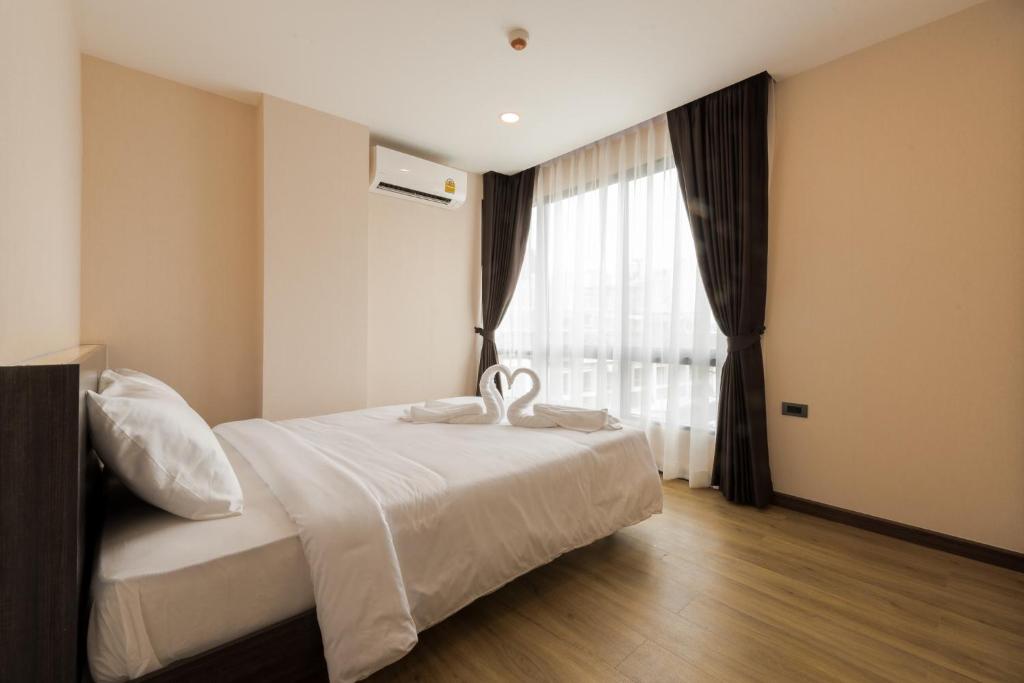 A simple bedroom with a double bed, full-height window, and dark curtains.