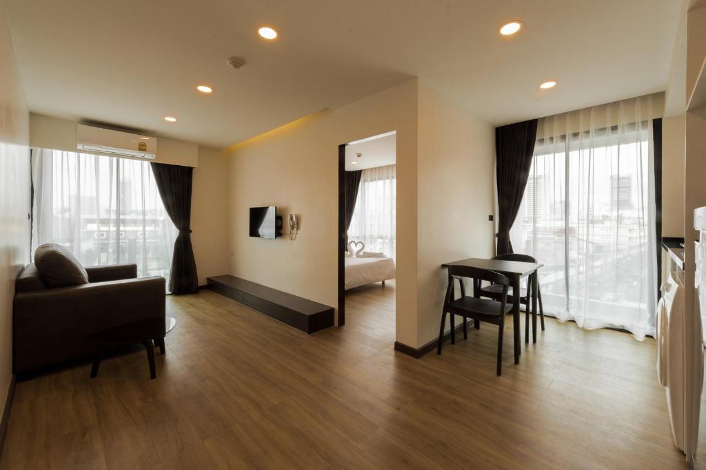 An open-plan residence living area with seating, dining space, a television, and a bedroom beyond.