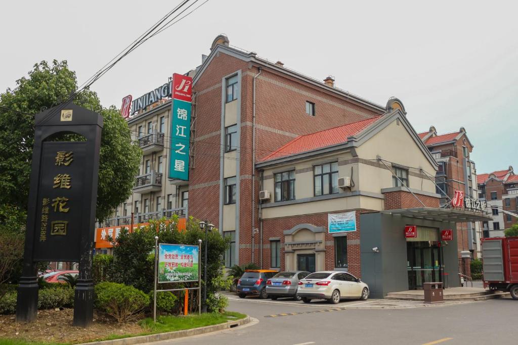 a street with cars parked in front of a building at Jinjiang Inn Shanghai Chedun Studios in Songjiang