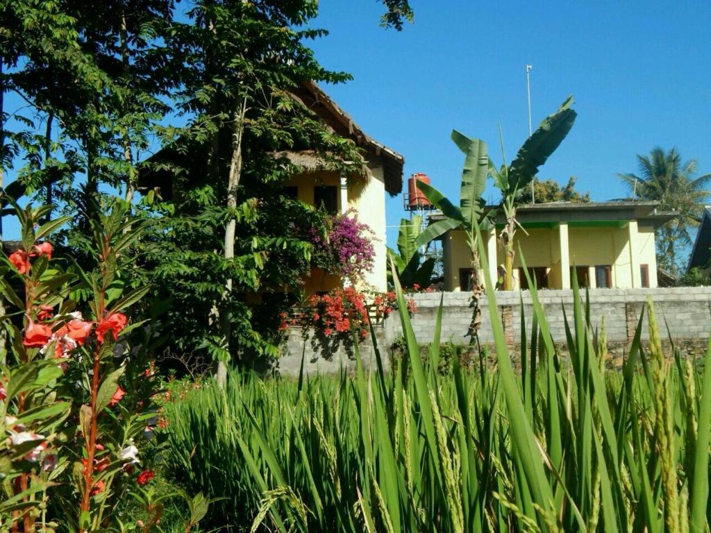 a house in front of a garden with flowers at Kembang Kuning Cottages in Tetebatu