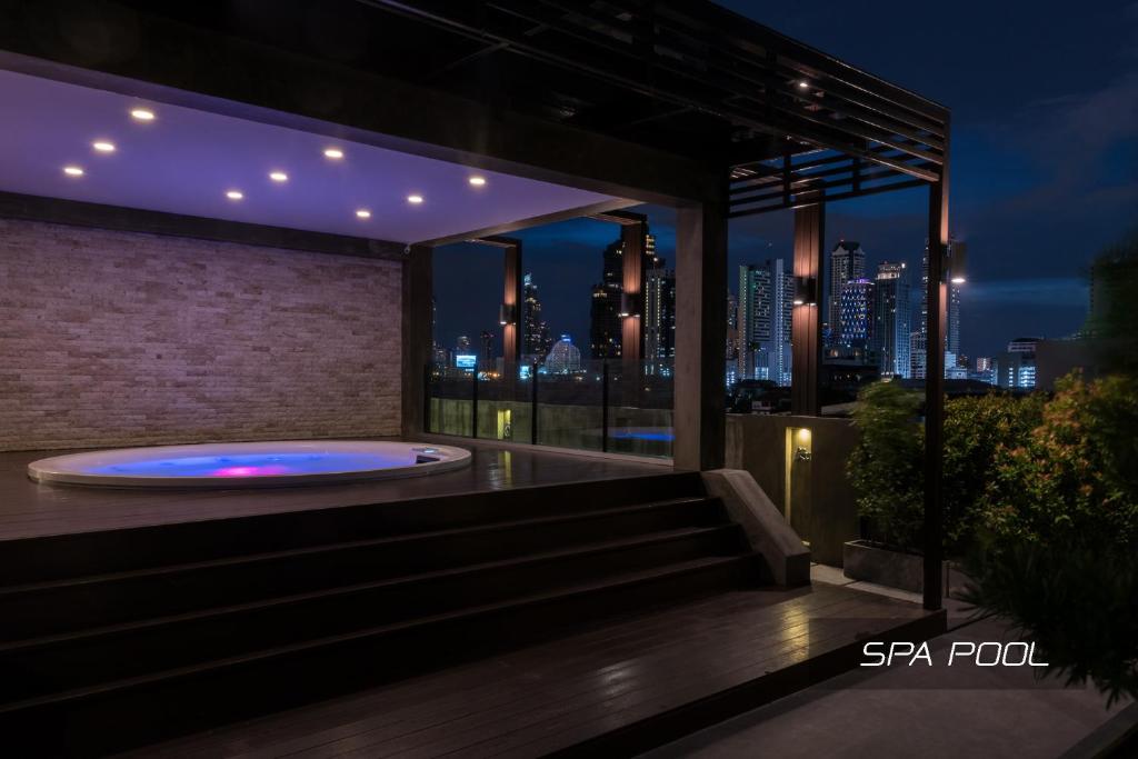 a hot tub on a balcony with a view of the city at Zensation The Residence in Bangkok