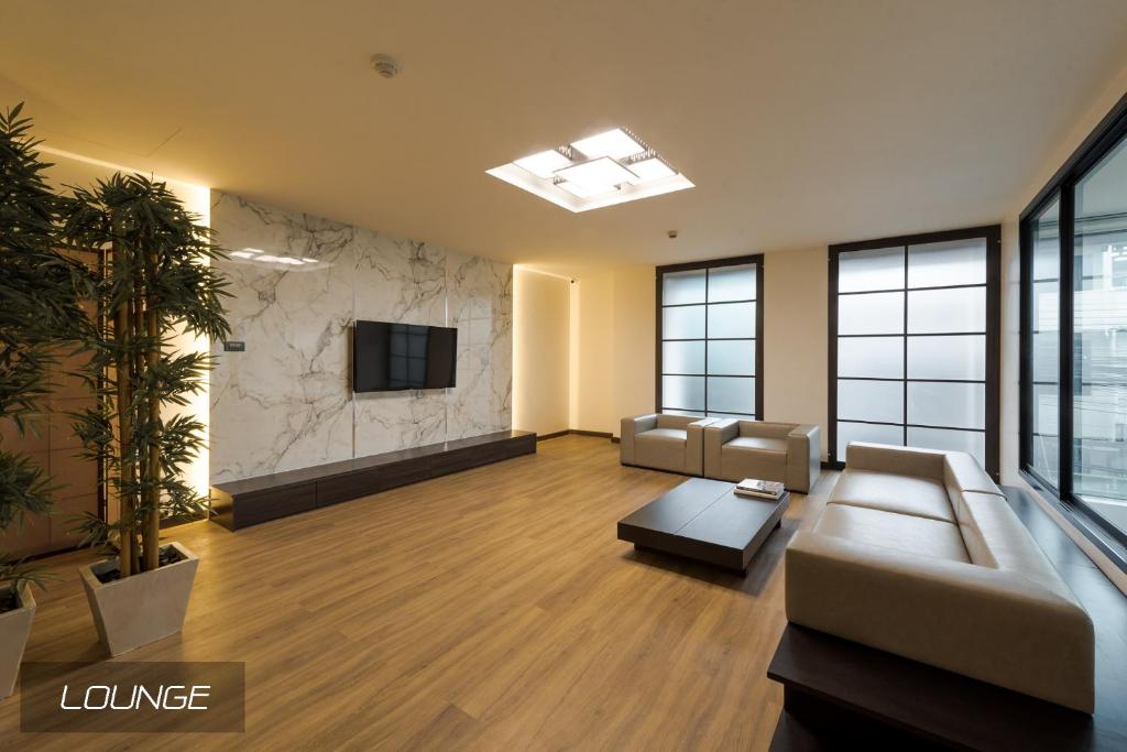 A spacious lounge with sofas, a wall-mounted TV and full-height windows.