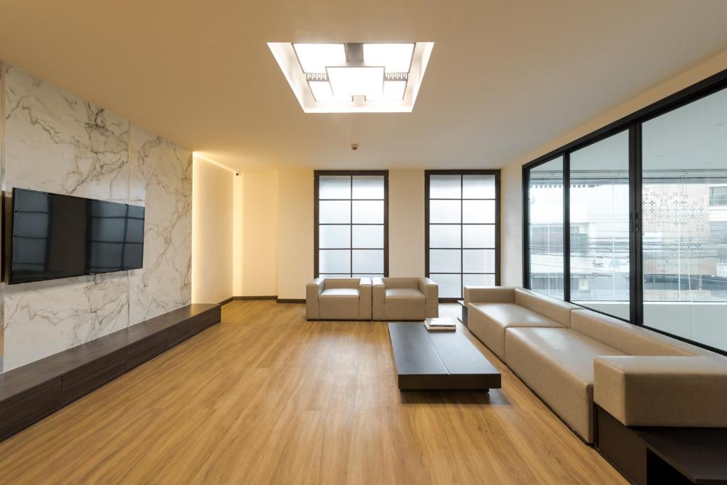 A spacious communal lounge with sofas, a large TV and broad city-facing glazing.