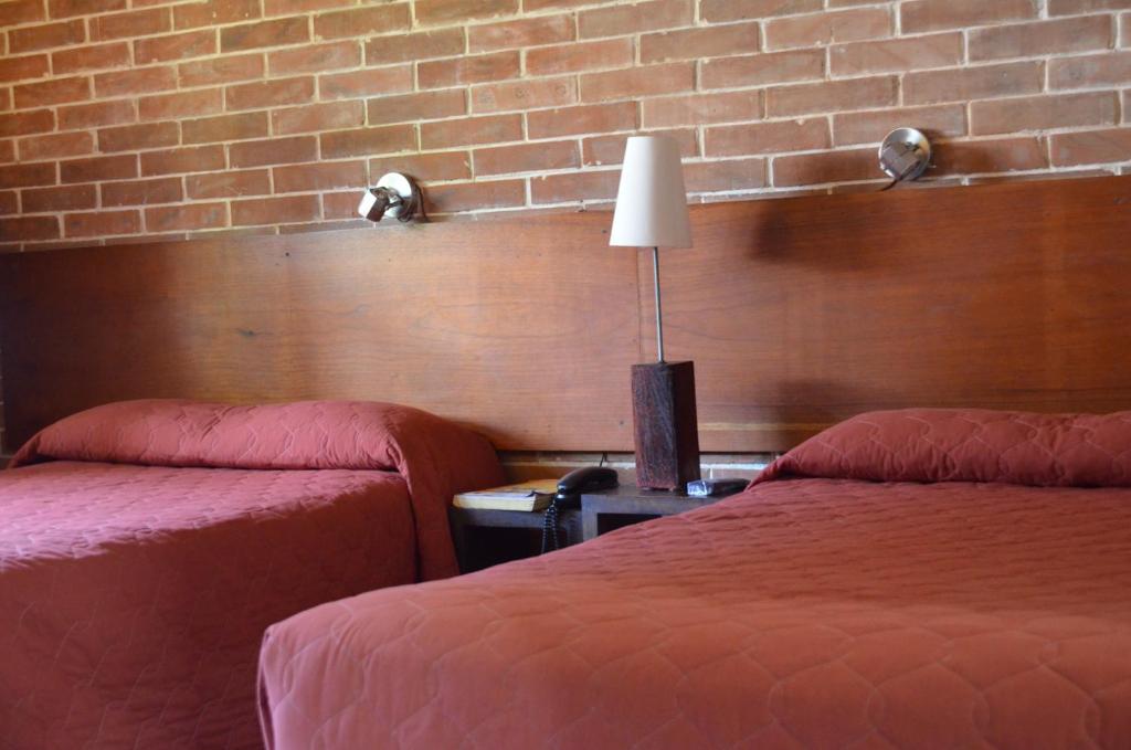 a hotel room with two beds and a brick wall at Dai Nonni Hotel in Guatemala