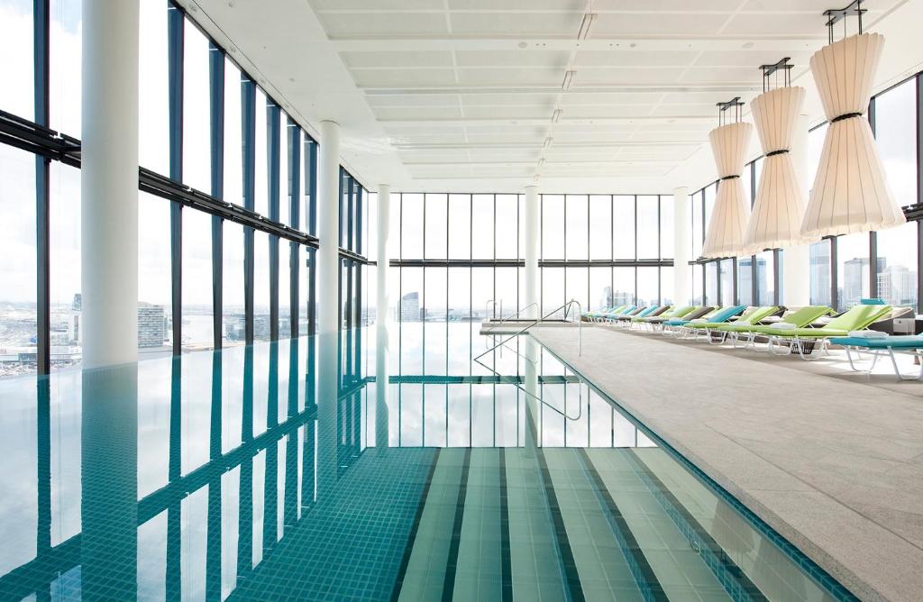 a pool in a building with chairs and windows at Crown Metropol Melbourne in Melbourne
