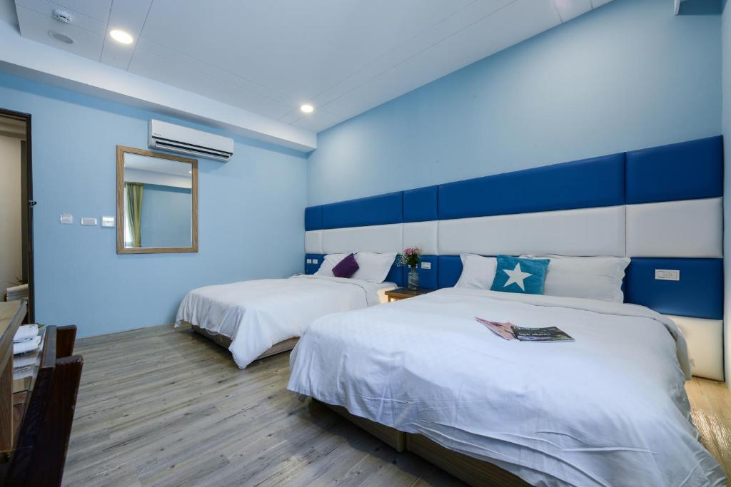 a blue room with two beds and a mirror at Kenting Coast Resort in Kenting