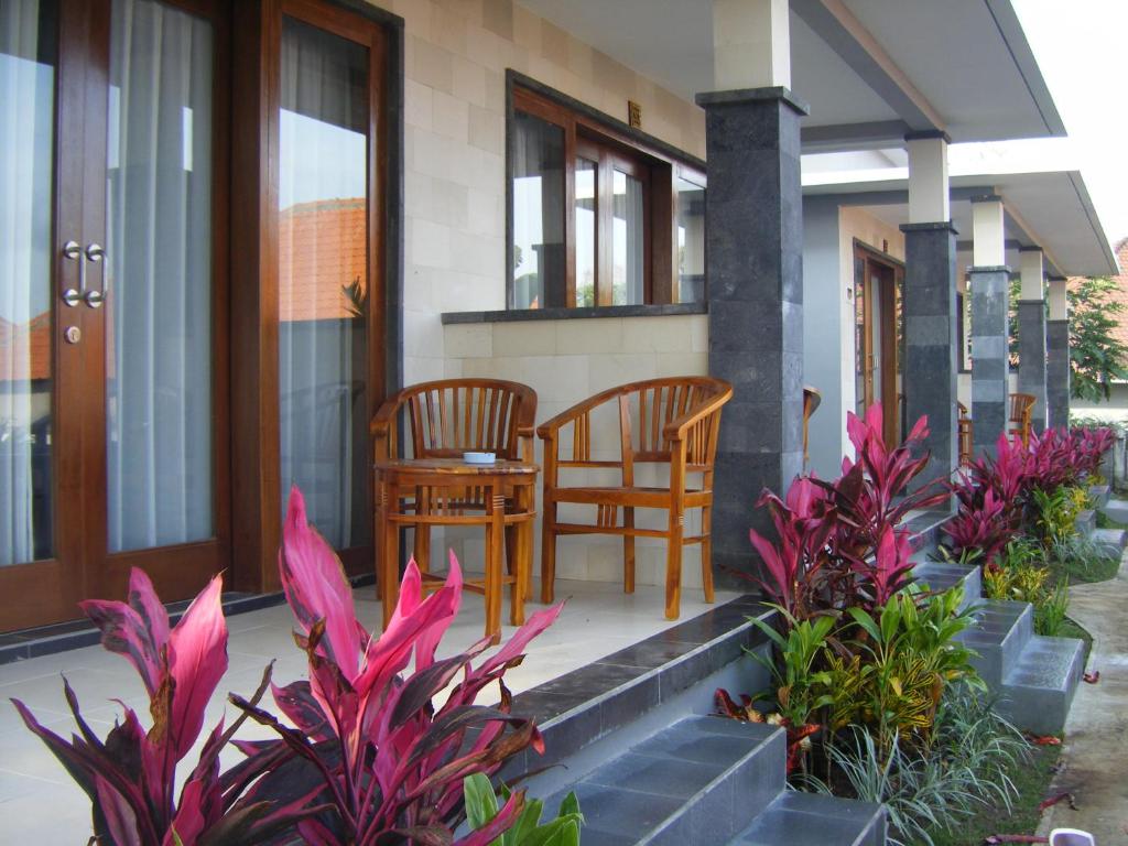 a porch of a house with two chairs and flowers at 3D Homestay in Uluwatu