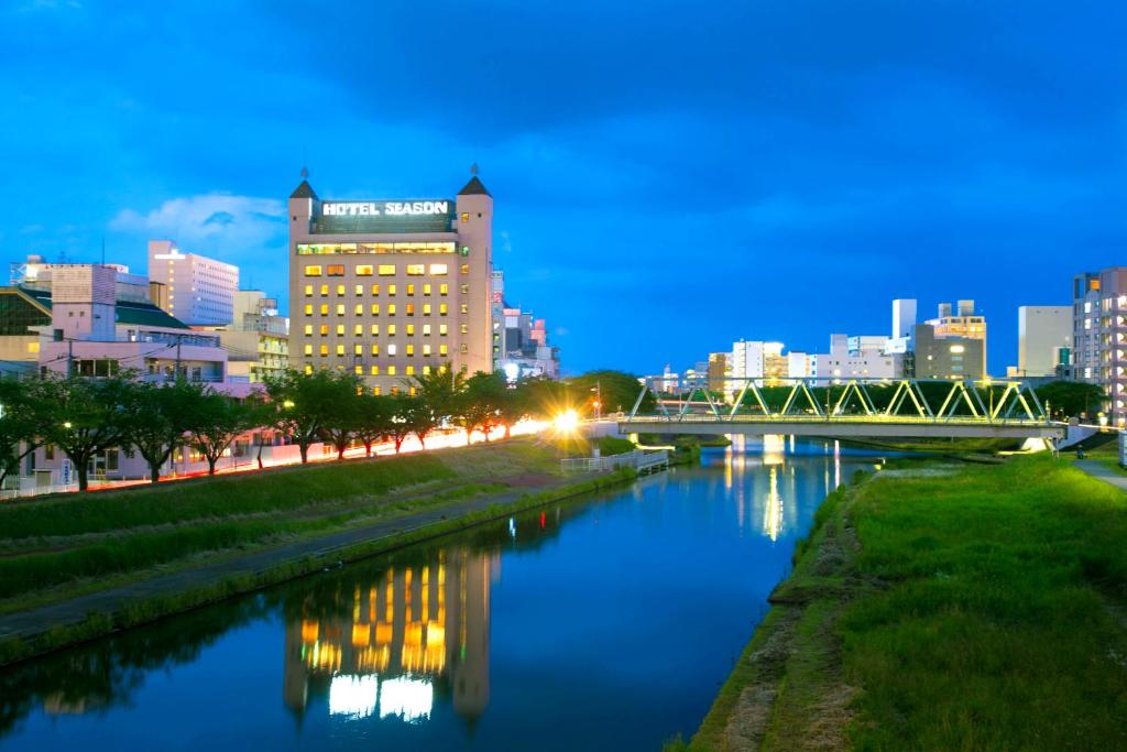 Una ciudad de noche con un río y un puente en Mito Hotel Season, en Mito