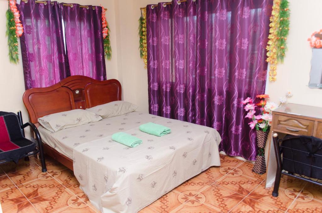 1 Schlafzimmer mit lila Vorhängen und 1 Bett mit 2 Handtüchern in der Unterkunft Julz Tropical Apartments in Olongapo