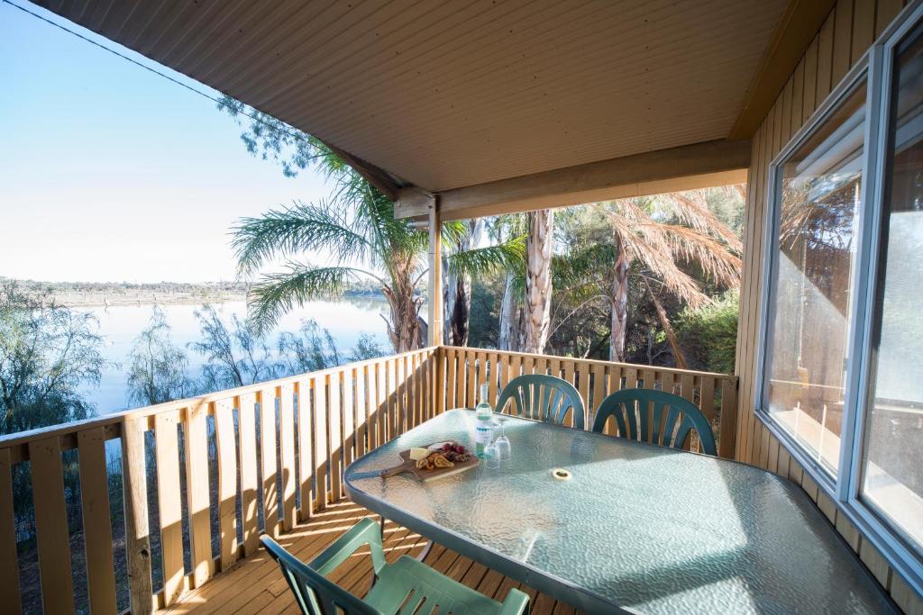 a wooden deck with a table and chairs on a balcony at Mundic Waterfront Cottages in Renmark