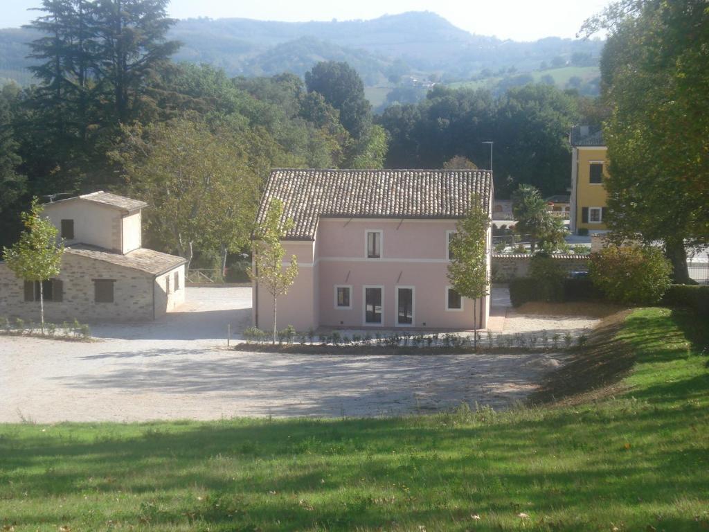 a large white house in the middle of a yard at Villa Collio Relais in San Severino Marche