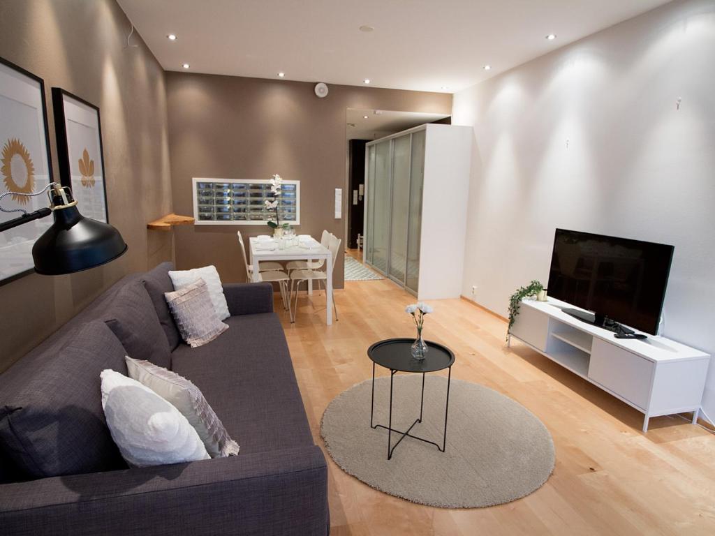 a living room with a couch and a flat screen tv at 2ndhomes Kamppi Center Apartment in Helsinki
