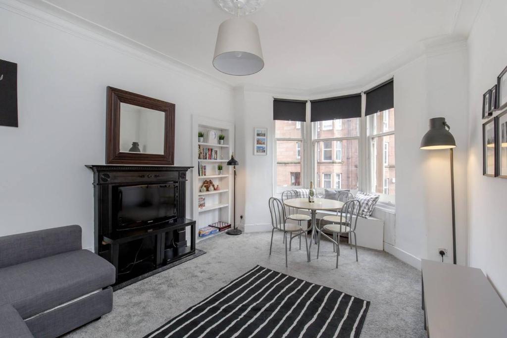 a living room with a couch and a table with chairs at Westend Glasgow Apartment in Glasgow