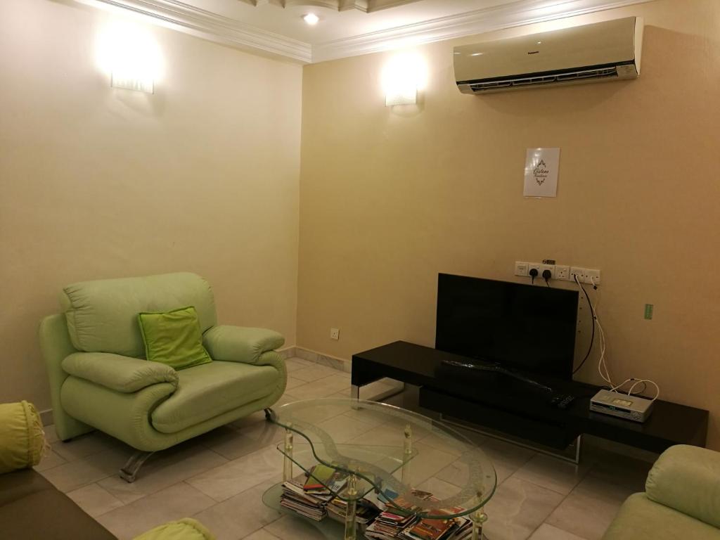 een woonkamer met een groene stoel en een televisie bij Vistana Residence, Bayan Lepas Penang in Bayan Lepas