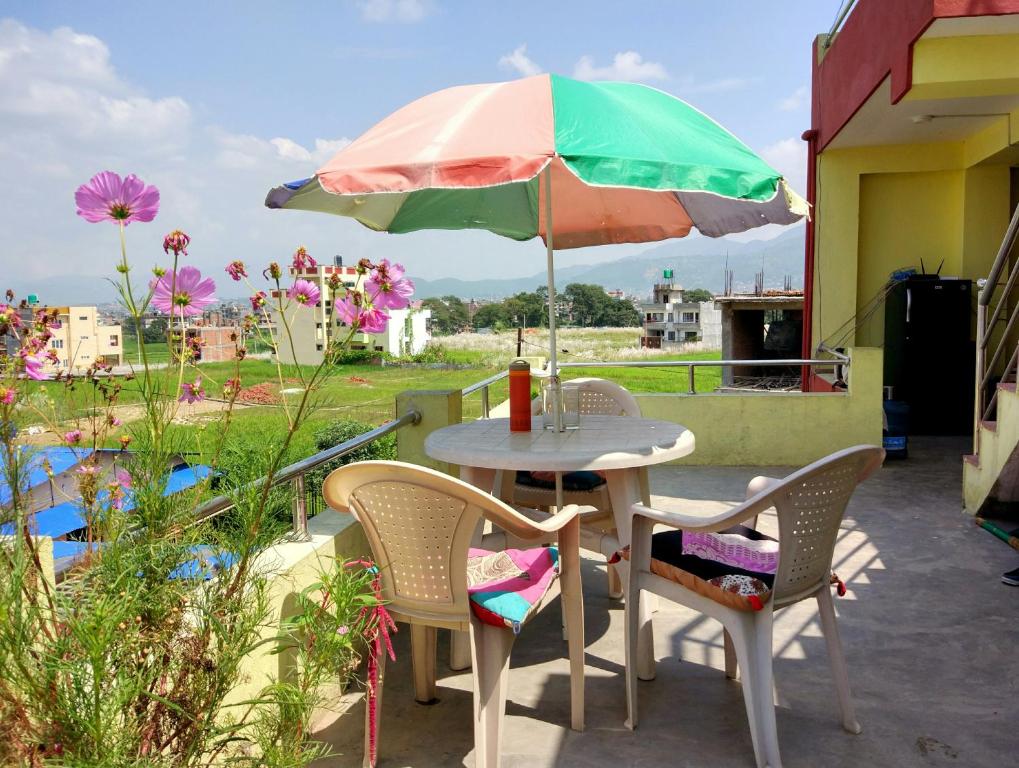 a table and chairs with an umbrella on a patio at Everest Home Stay Apartment in Pātan