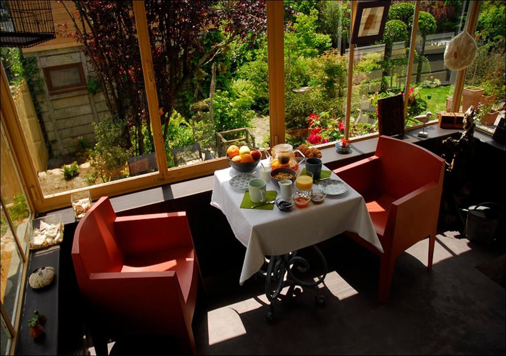 une table et des chaises dans une chambre avec une grande fenêtre dans l'établissement Jardin de Belle Vue, à Quimperlé