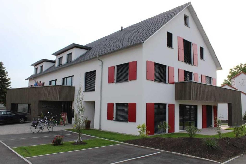 um grande edifício branco com janelas com persianas vermelhas em FeWo Daiber em Bad Schussenried